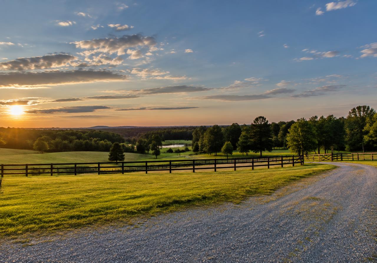Rolling Piedmont pasture with a fence and gravel drive (AI-generated image)
